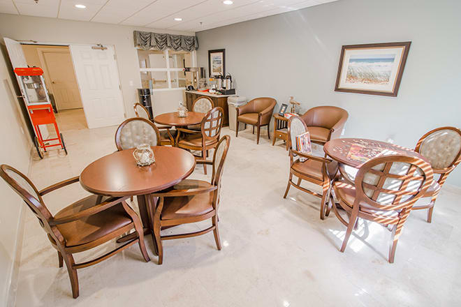 A cozy dining area with several tables and chairs, featuring simple decor and ample lighting.