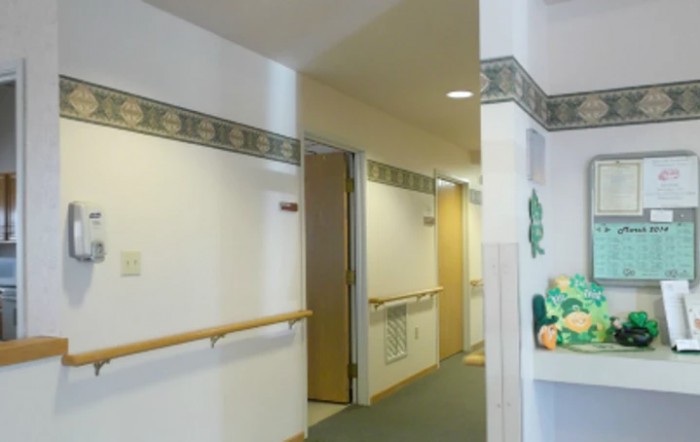 A hallway with multiple doors and a handrail along the wall.
