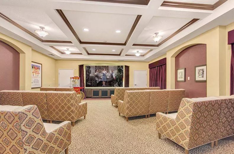 A cozy theater room with patterned seating and a large projector screen.