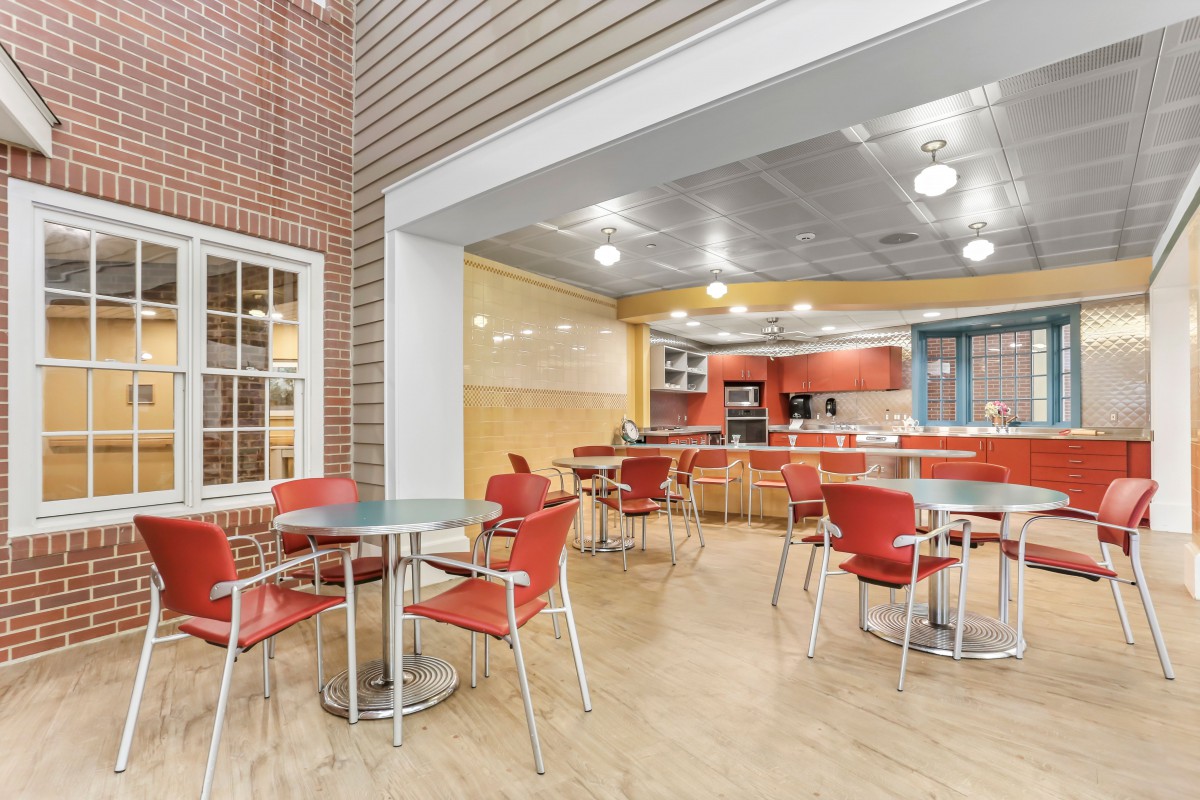 A modern cafe with red chairs and tables, featuring bright lighting and a casual ambiance.