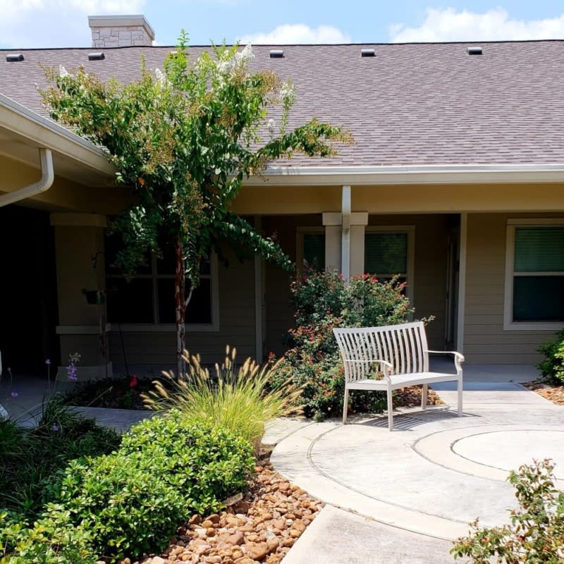 A cozy house with a landscaped garden, featuring a bench and pathway.