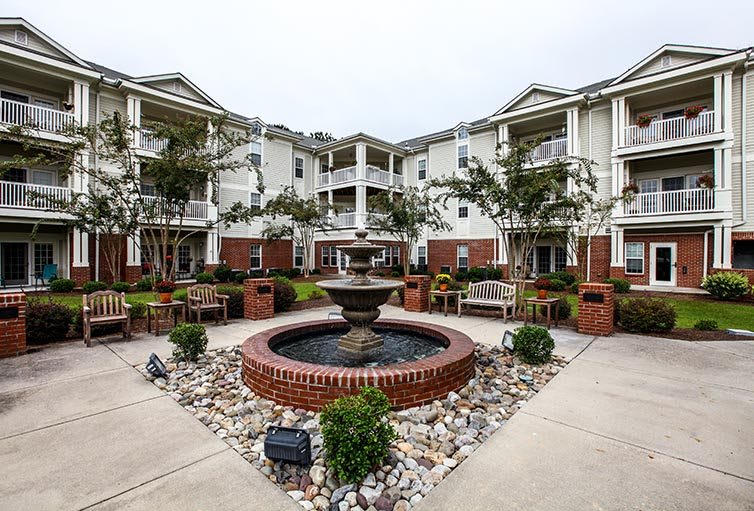 A beautifully landscaped courtyard with a central fountain surrounded by a residential building.