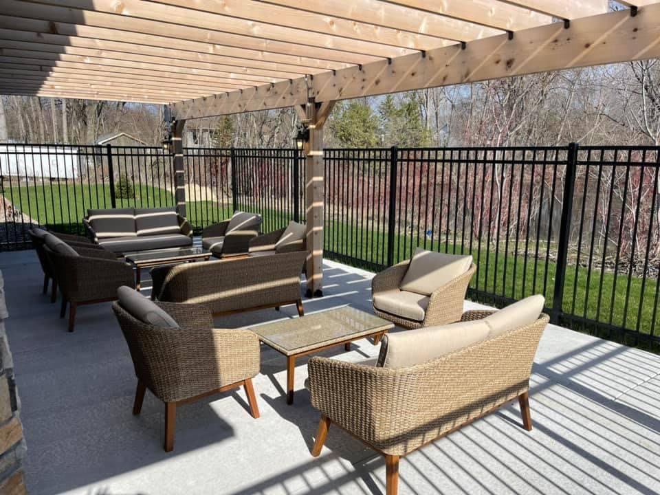 Outdoor patio with wicker furniture under a wooden pergola.