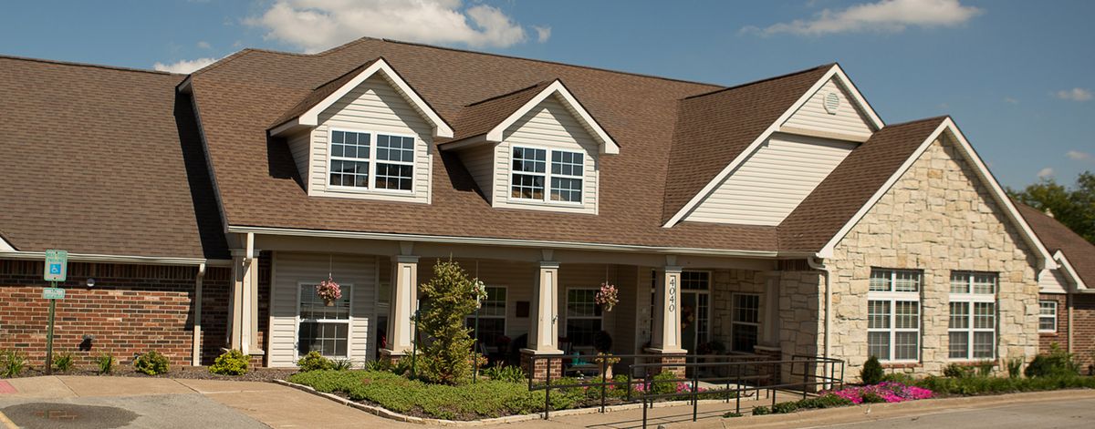 A large residential house with a front yard and a gabled roof under a clear sky.