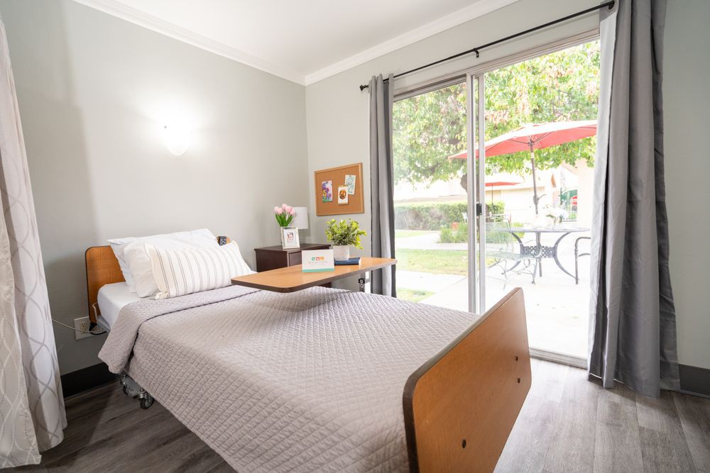 A minimalist bedroom featuring a hospital-style bed with a view of a patio through sliding glass doors.