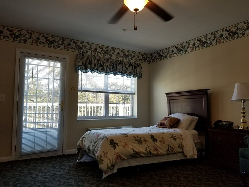 A cozy bedroom with a single bed, ceiling fan, and floral wallpaper.