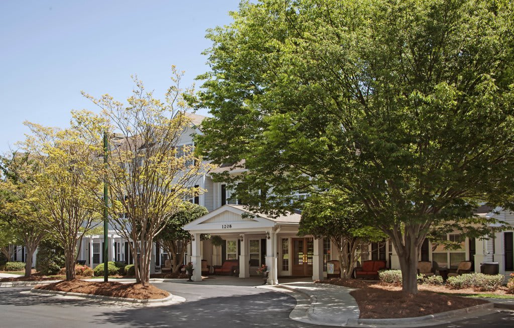 A front view of a building entrance surrounded by lush trees.