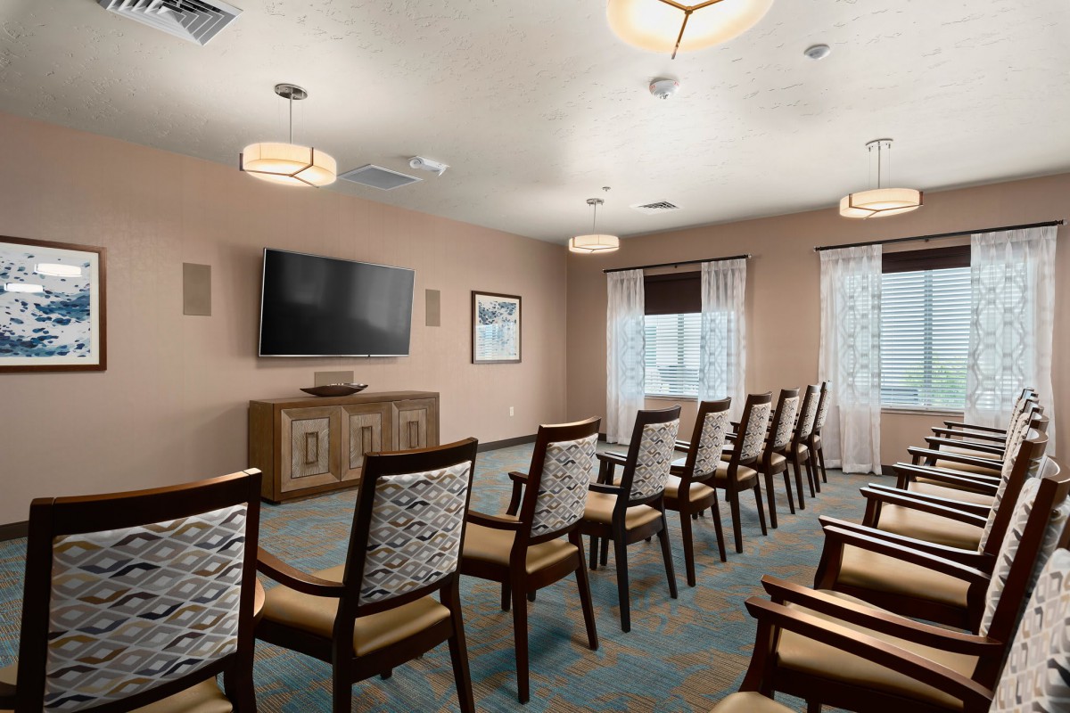 A well-organized conference room with rows of chairs facing a large television.