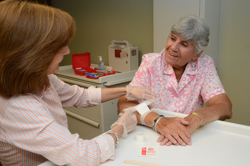 A nurse is attending to an elderly patient during a medical examination.