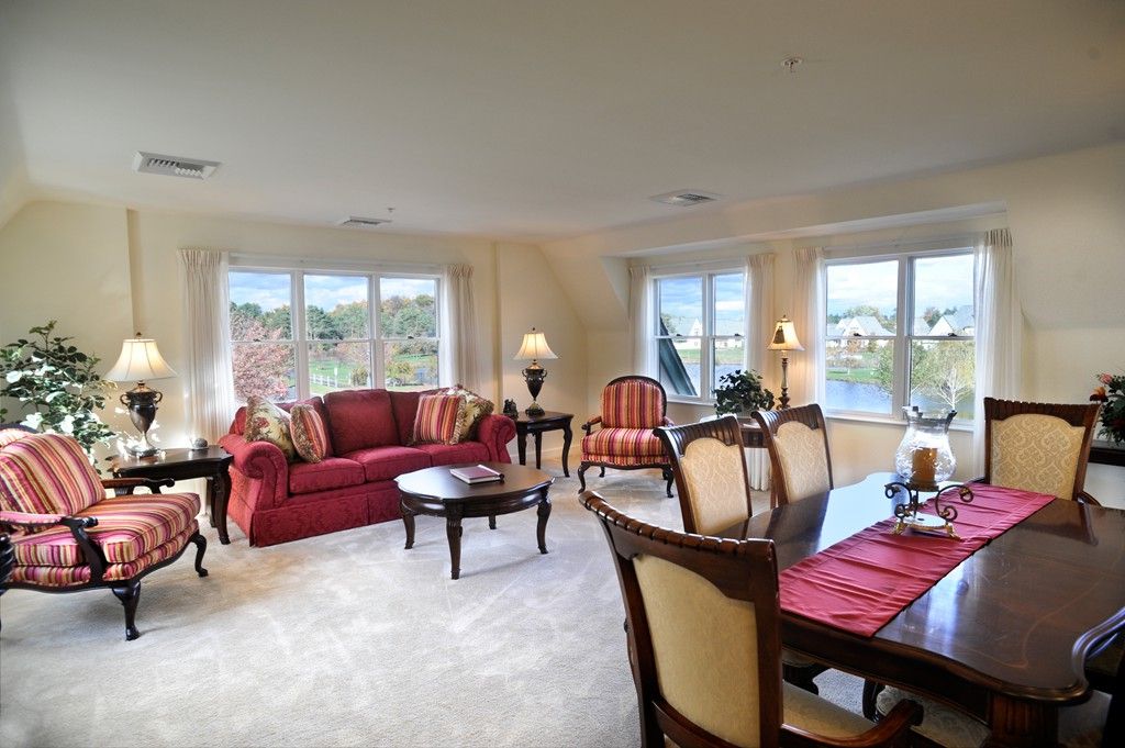 A spacious living and dining area with elegant furniture and large windows overlooking a lake.