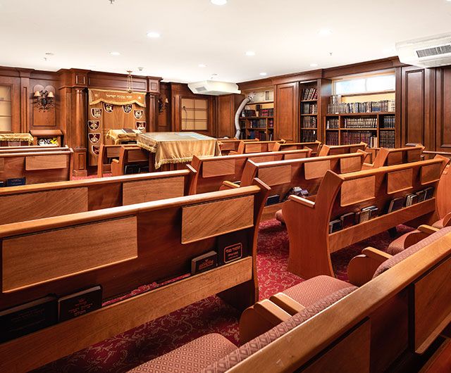 Interior of a synagogue featuring wooden benches and bookshelves.