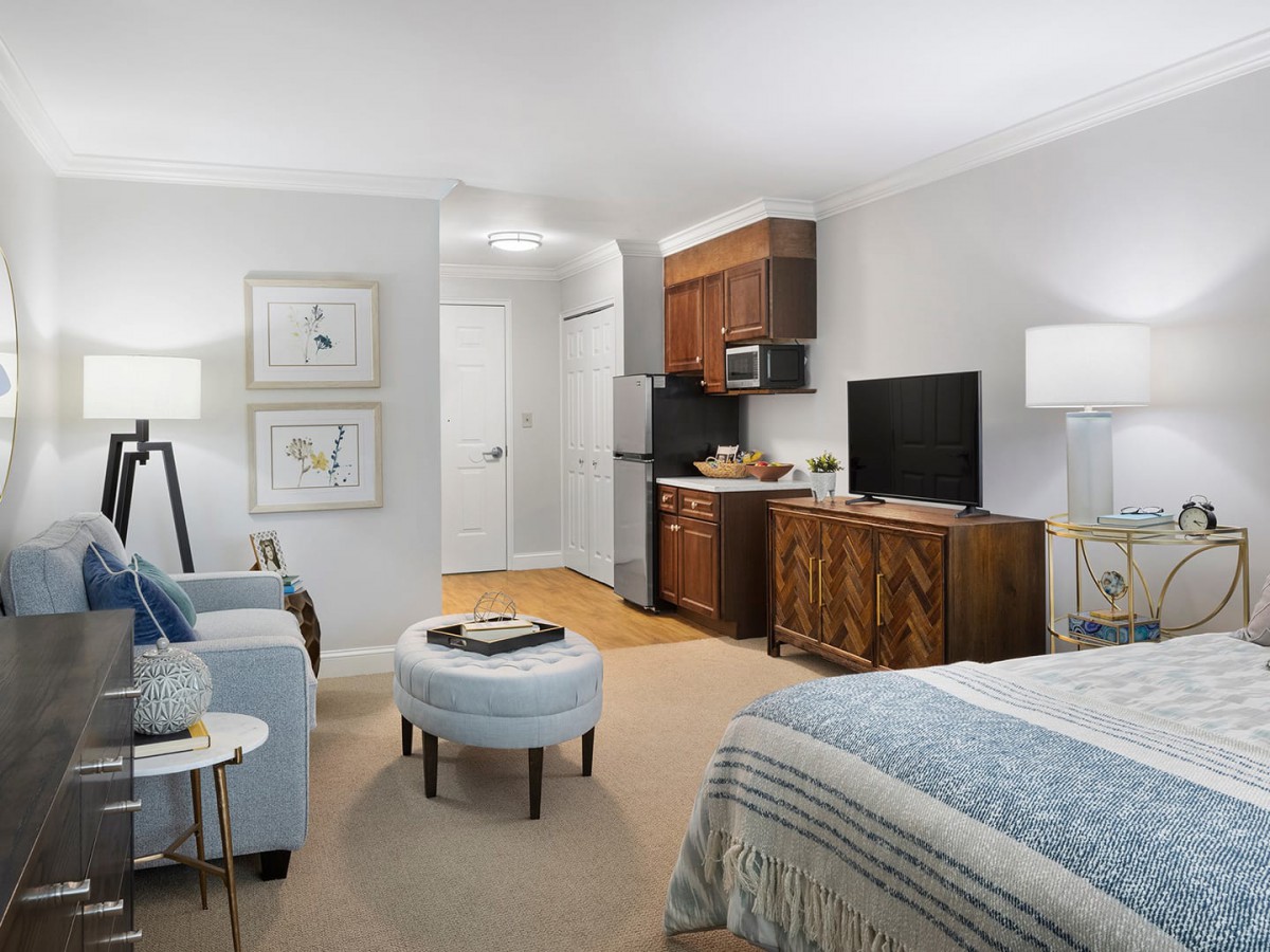 A cozy studio apartment with a combined living and sleeping area, featuring a small kitchenette and modern furnishings.