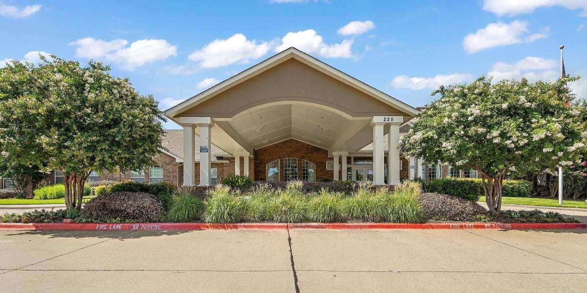 A large building entrance with a covered walkway and landscaped surroundings.