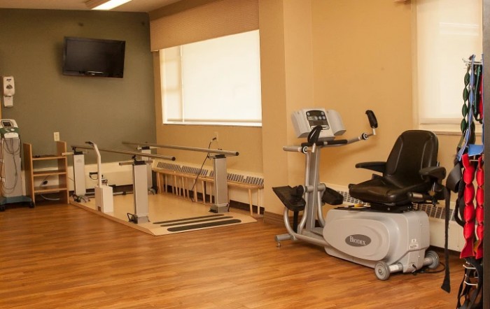 A physical therapy room equipped with exercise machines and parallel bars.