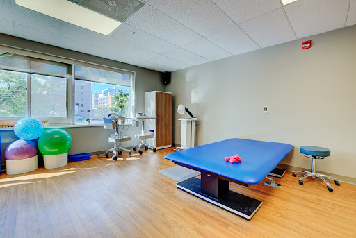 A well-equipped physical therapy room featuring a blue treatment table and various exercise tools, designed for rehabilitation purposes.