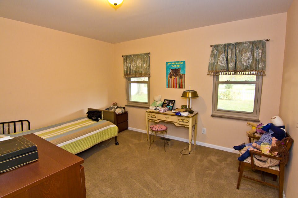 A vintage bedroom with a bed, desk, and decor.