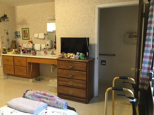 A cozy room featuring a dresser, a television, and a mirror, suggesting a personal space possibly in a healthcare setting.