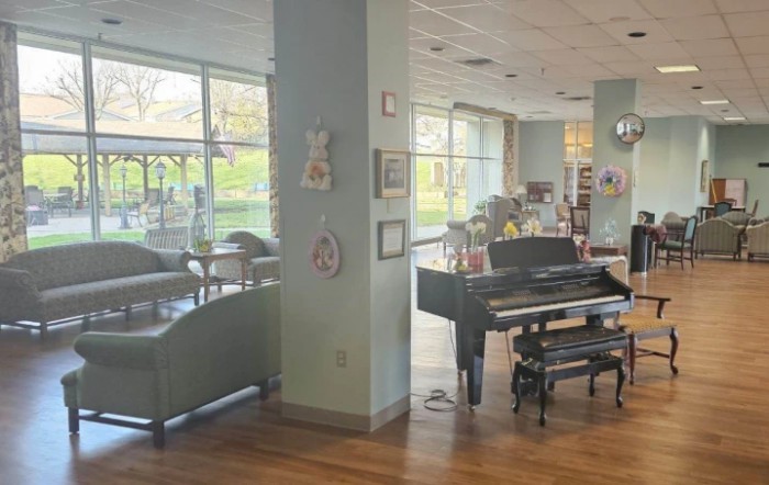A cozy lounge area featuring a piano and comfortable seating with large windows.