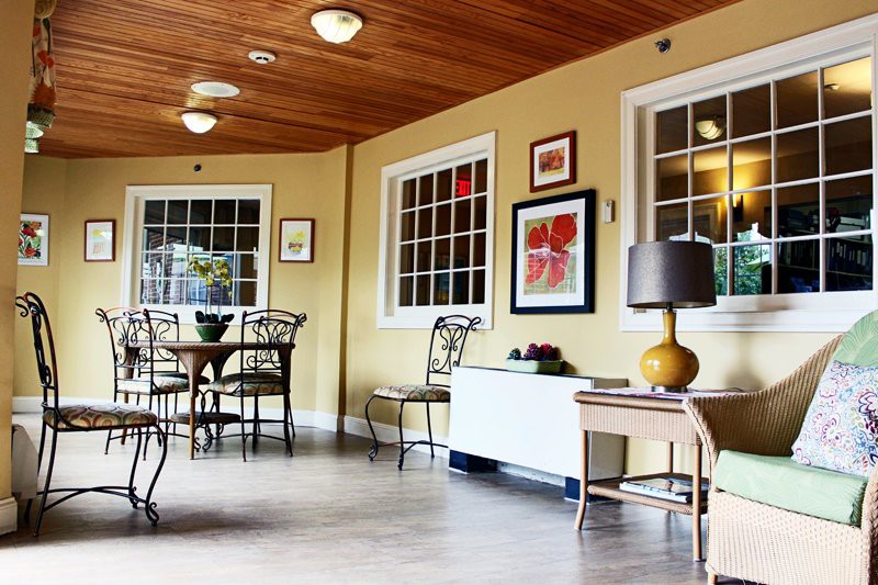 A cozy interior space featuring tables, chairs, and decorative artwork, with warm lighting.