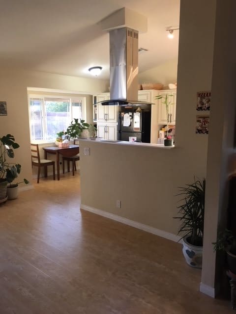 An open-plan kitchen and dining area with wooden flooring and indoor plants.