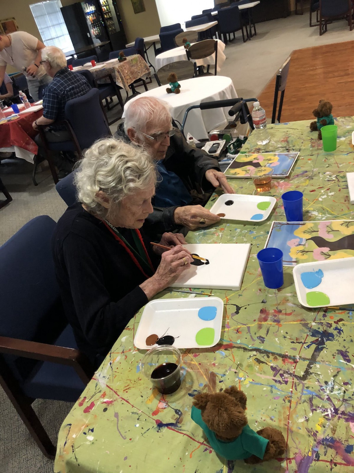 Elderly individuals participating in a painting activity.