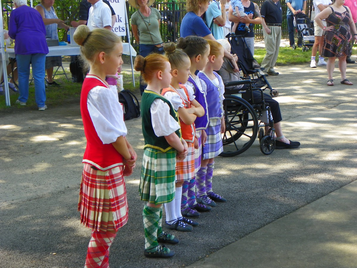 Children dressed in traditional costumes preparing to dance at an outdoor festival.