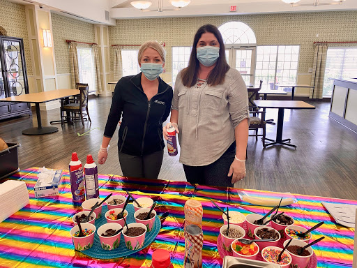 Two women enjoying a festive dessert event indoors, surrounded by various sweet treats.