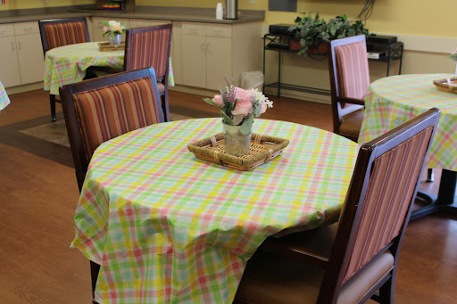 A cozy dining area featuring a round table dressed with a colorful checkered tablecloth and a decorative arrangement of flowers.