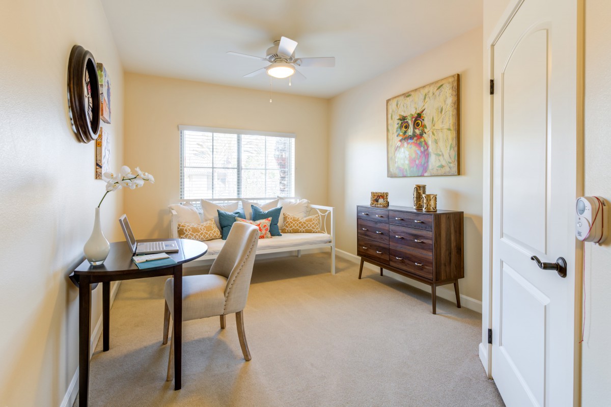A cozy home office space with a desk, chair, sofa, and decorative artwork.