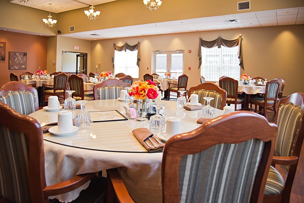 A well-decorated dining room with neatly arranged tables and chairs, featuring floral centerpieces.