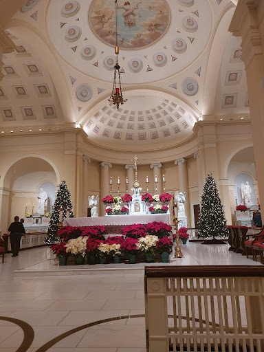 A beautifully decorated church interior for the Christmas season, featuring an ornate altar surrounded by festive poinsettias and Christmas trees.