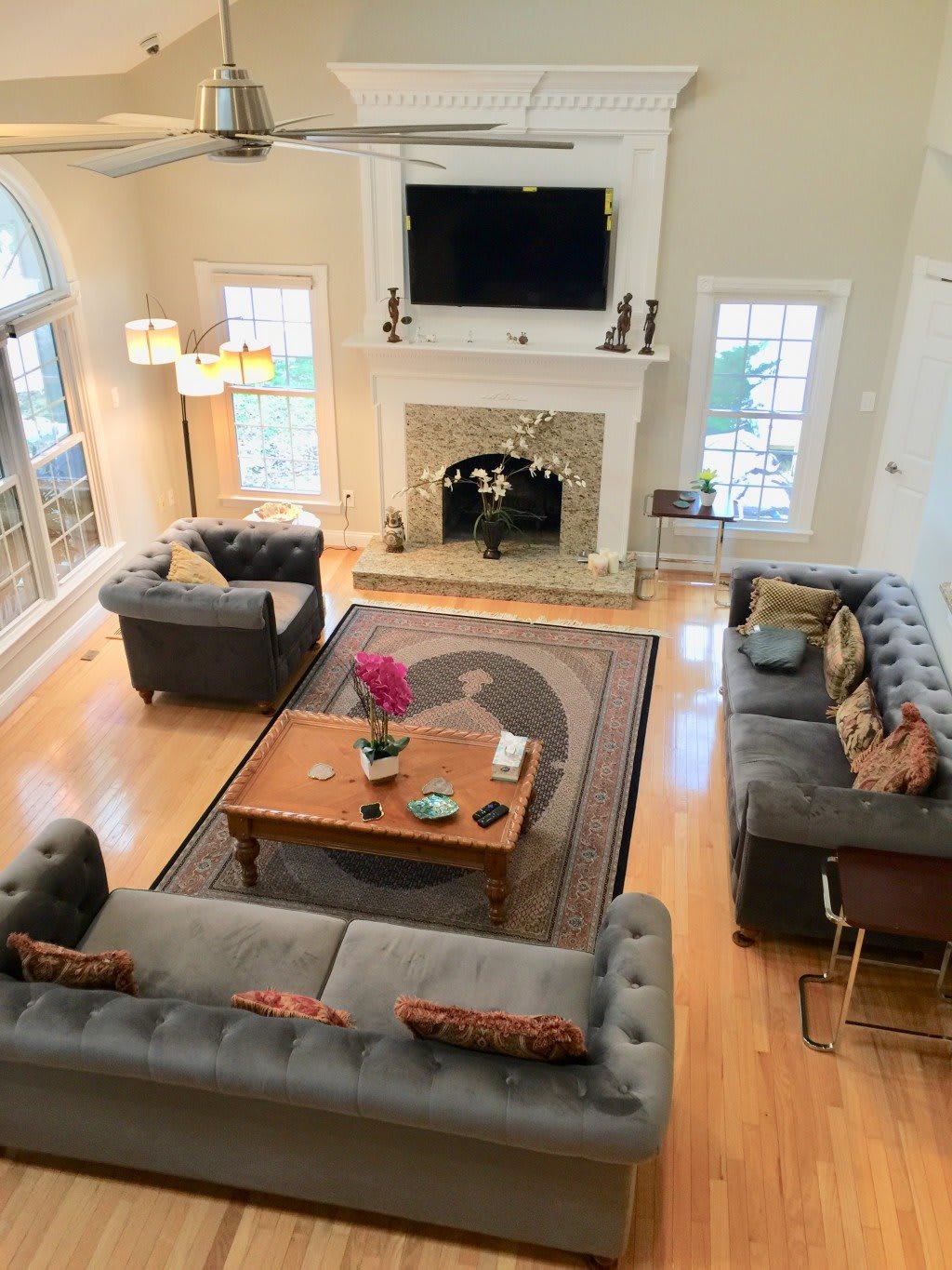 A spacious living room with contemporary decor, featuring a central coffee table, stylish sofas, a fireplace, and a wall-mounted television.