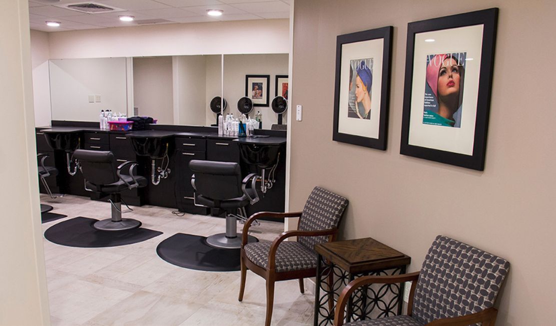 An empty salon interior with styling chairs, mirrors, and framed wall art.