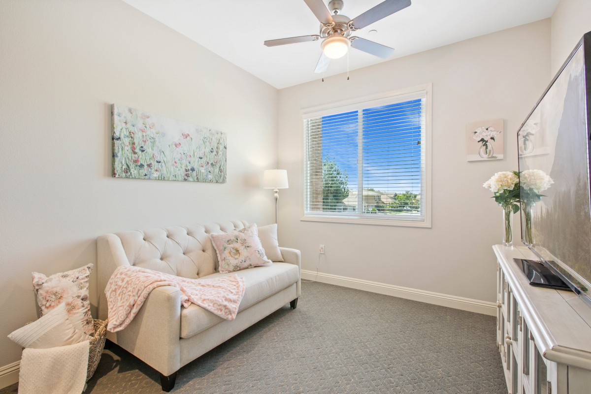 A cozy living room with a sofa, brightened by natural light from the window.