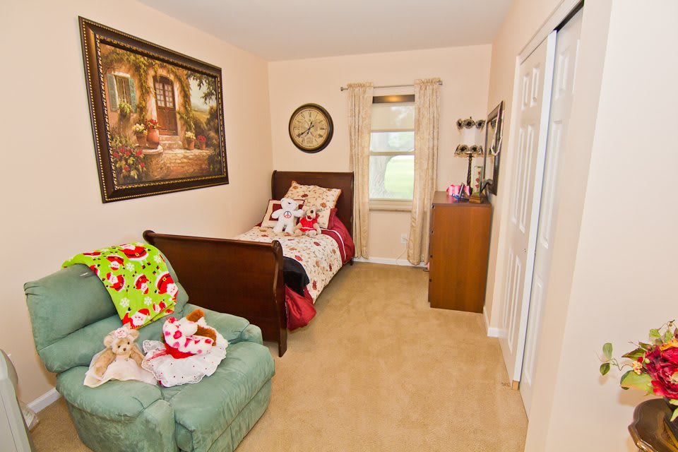 A cozy child's bedroom featuring a twin bed, a plush chair, and charming wall decor.