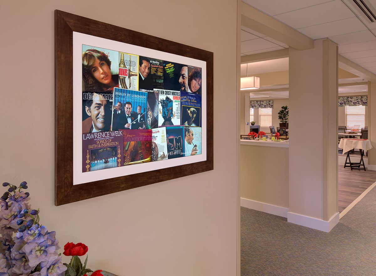 A framed collage of music posters displayed on a hallway wall.