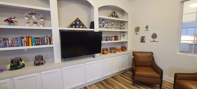 A living room with built-in shelves displaying decorative items, a television, and flag display cases.