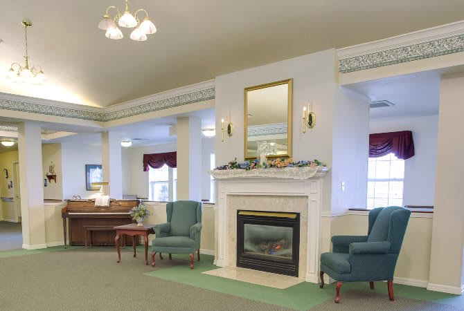 A cozy living room with a fireplace, two armchairs, and a piano.