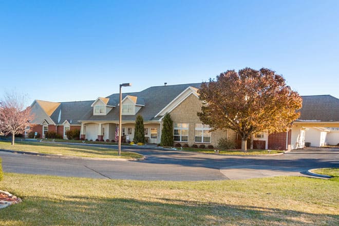 A suburban residential building with a well-maintained lawn and trees under a clear blue sky.
