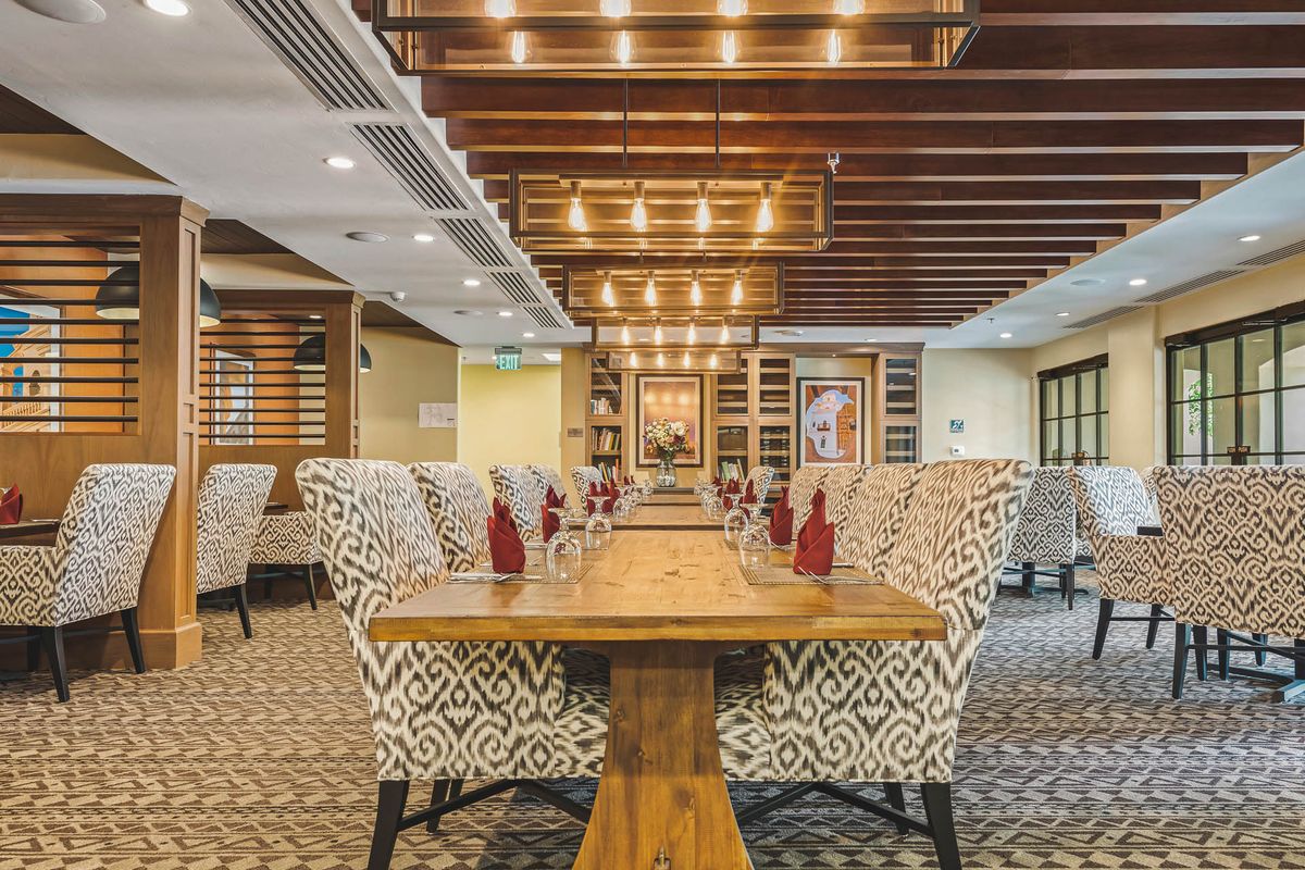 Elegant restaurant interior with a beautifully set dining table and patterned chairs.
