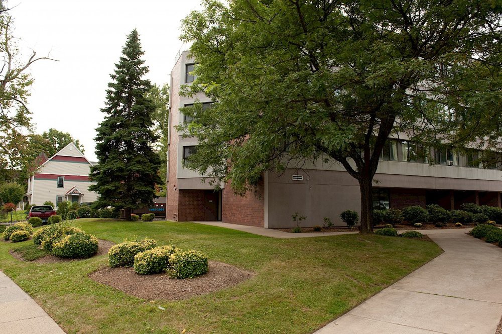 A residential building surrounded by trees and well-maintained landscaping.