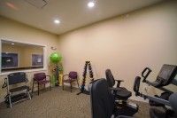 A small exercise room with various fitness equipment and chairs.