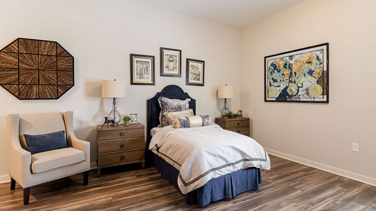 A cozy bedroom with a single bed, complemented by nightstands, lamps, and framed artwork on the walls.