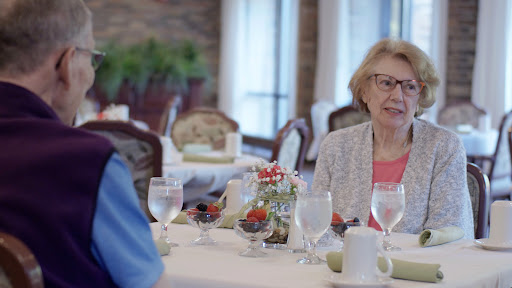 An elderly woman enjoying a conversation over lunch in a cozy restaurant setting.