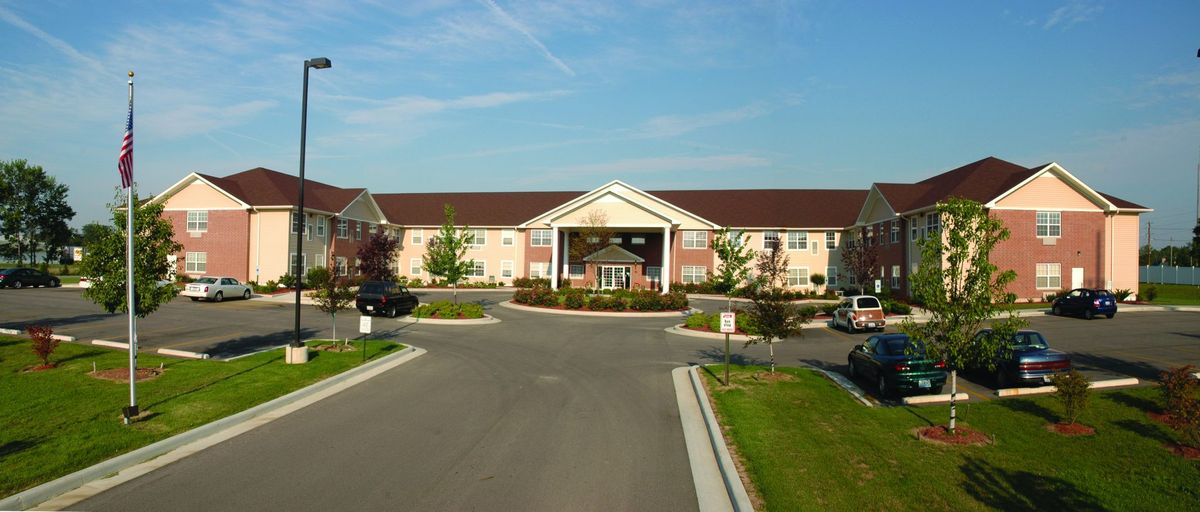 A hotel building with a driveway and landscaped entrance on a clear day.