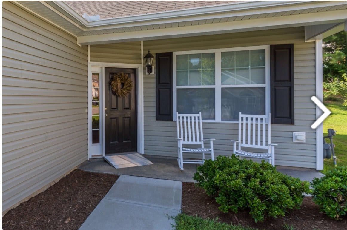 A cozy front porch with two white rocking chairs beside the entrance.