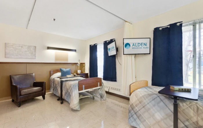 A shared hospital room with two beds, TV screens, and cozy furnishings.