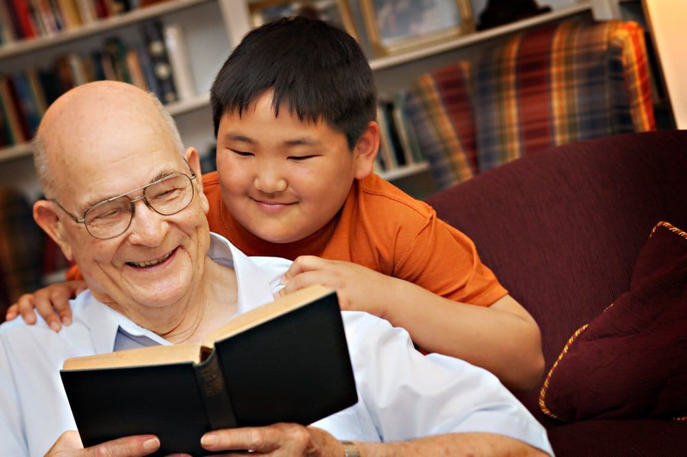 A grandfather and his grandson enjoying a book together.