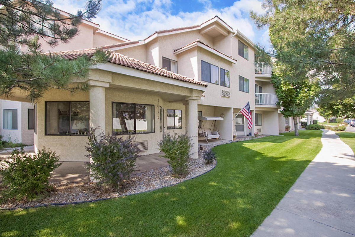 A residential apartment complex with a well-maintained lawn and an American flag displayed.