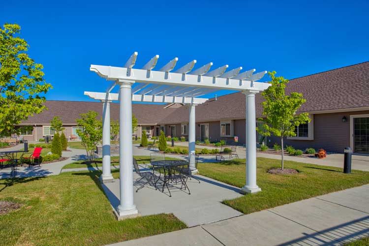 A sunny outdoor patio area featuring a white pergola and seating.